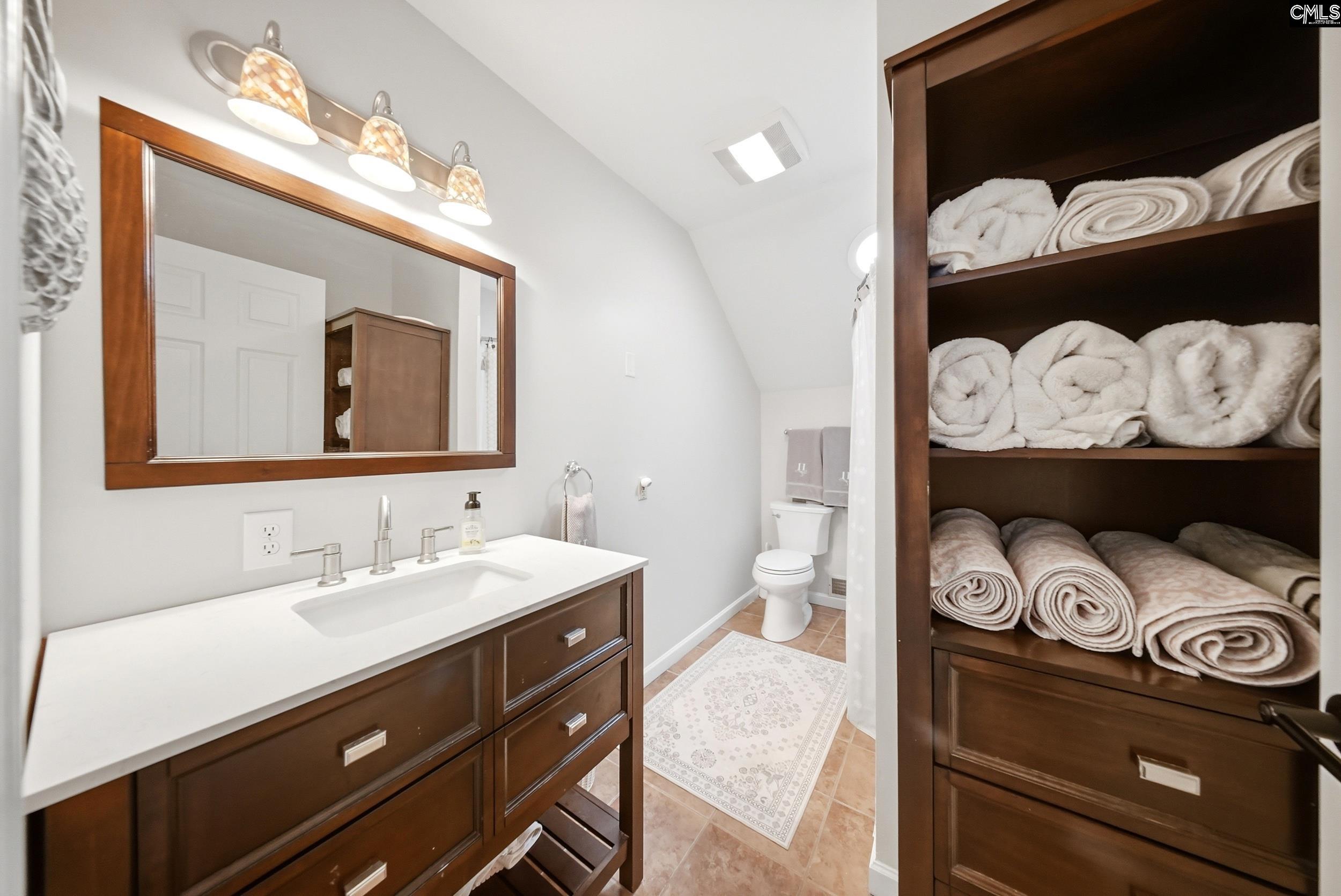 Bathroom with a dark wood vanity and built-in shelves filled with neatly rolled towels.