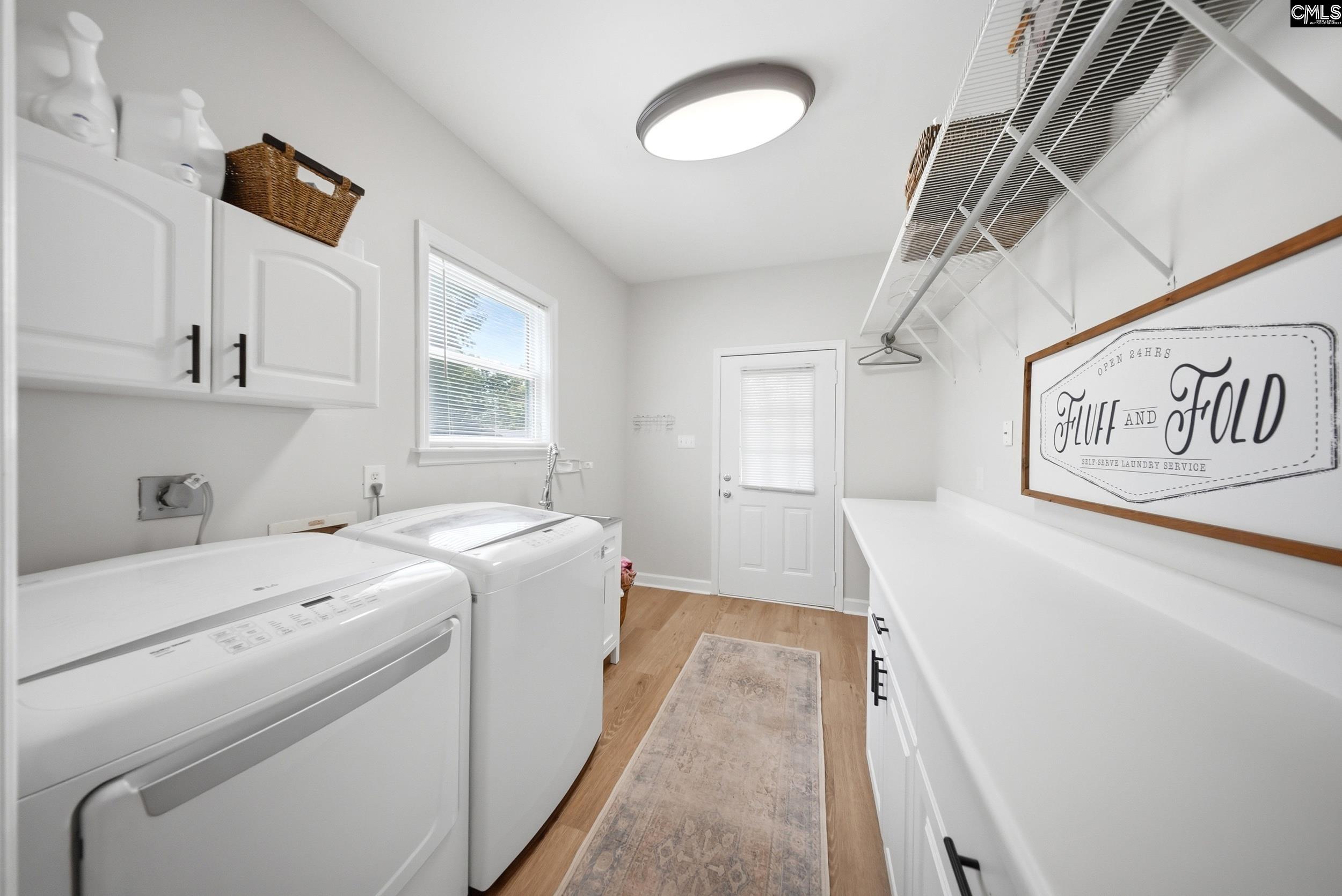 Laundry room with washer and dryer, white cabinets, overhead storage racks, and a long folding counter.