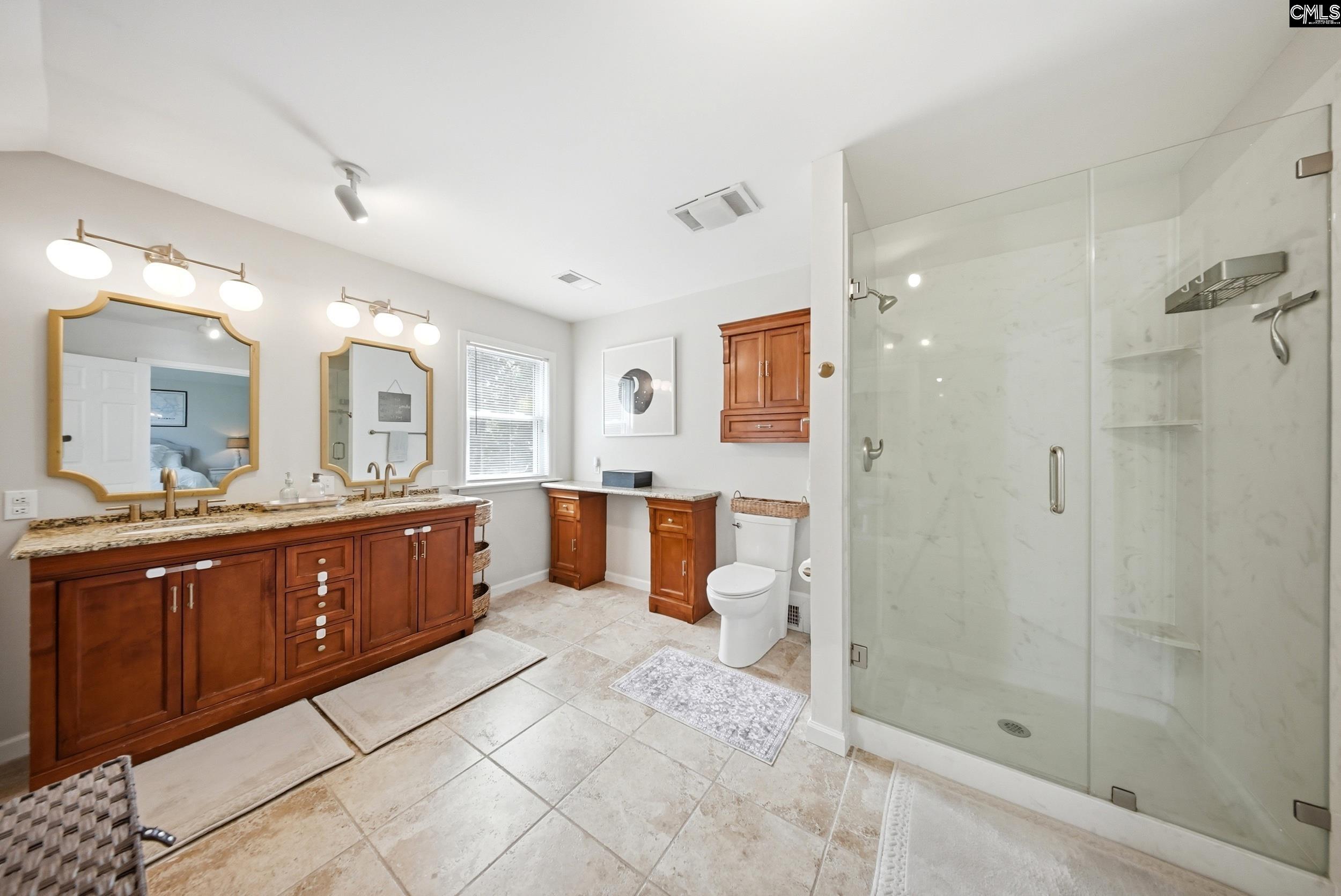 Bathroom with a long cherry-wood double vanity and a spacious glass-enclosed shower.