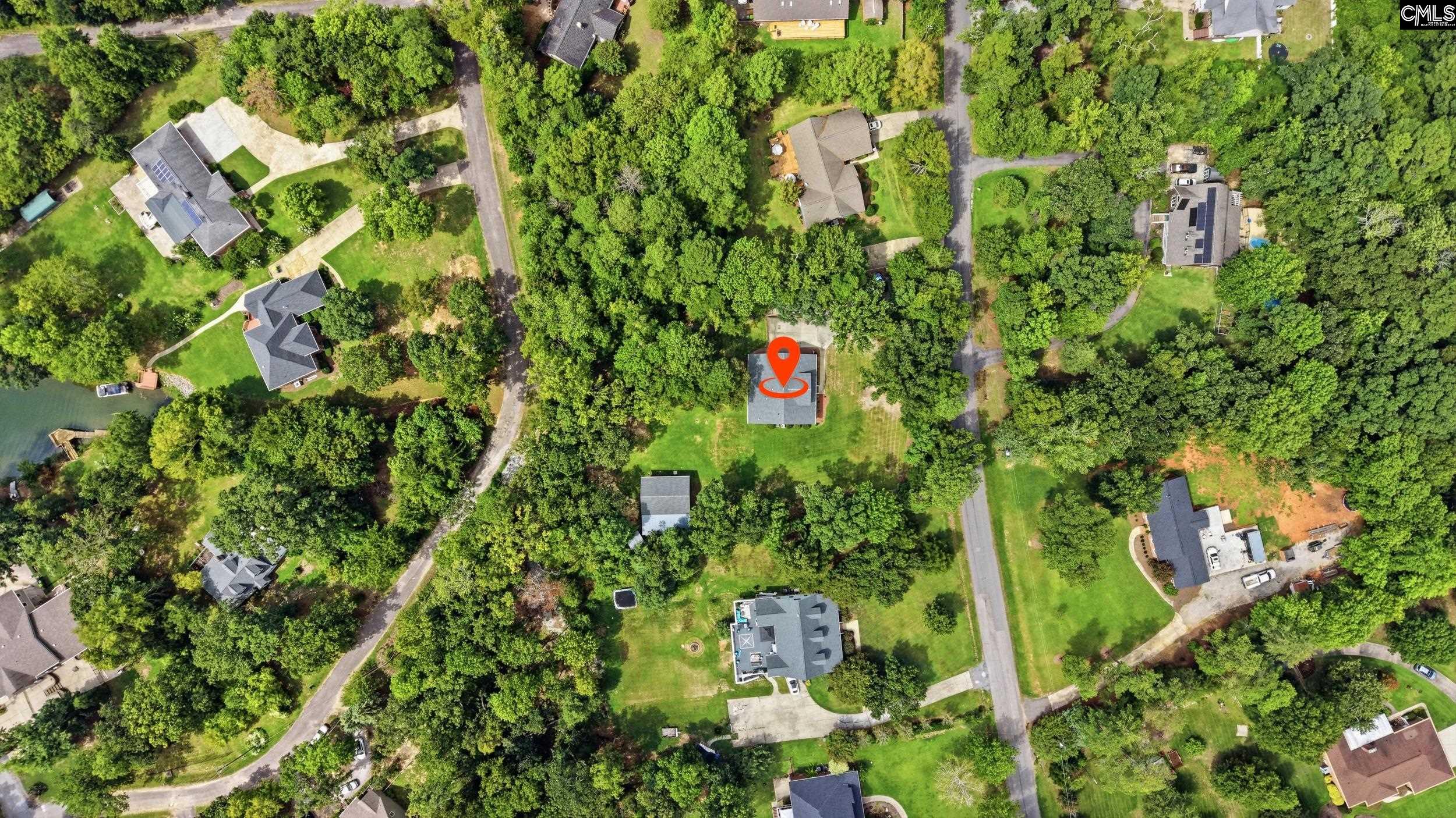 Aerial view of the marked home among wooded lots, with nearby roads and water.