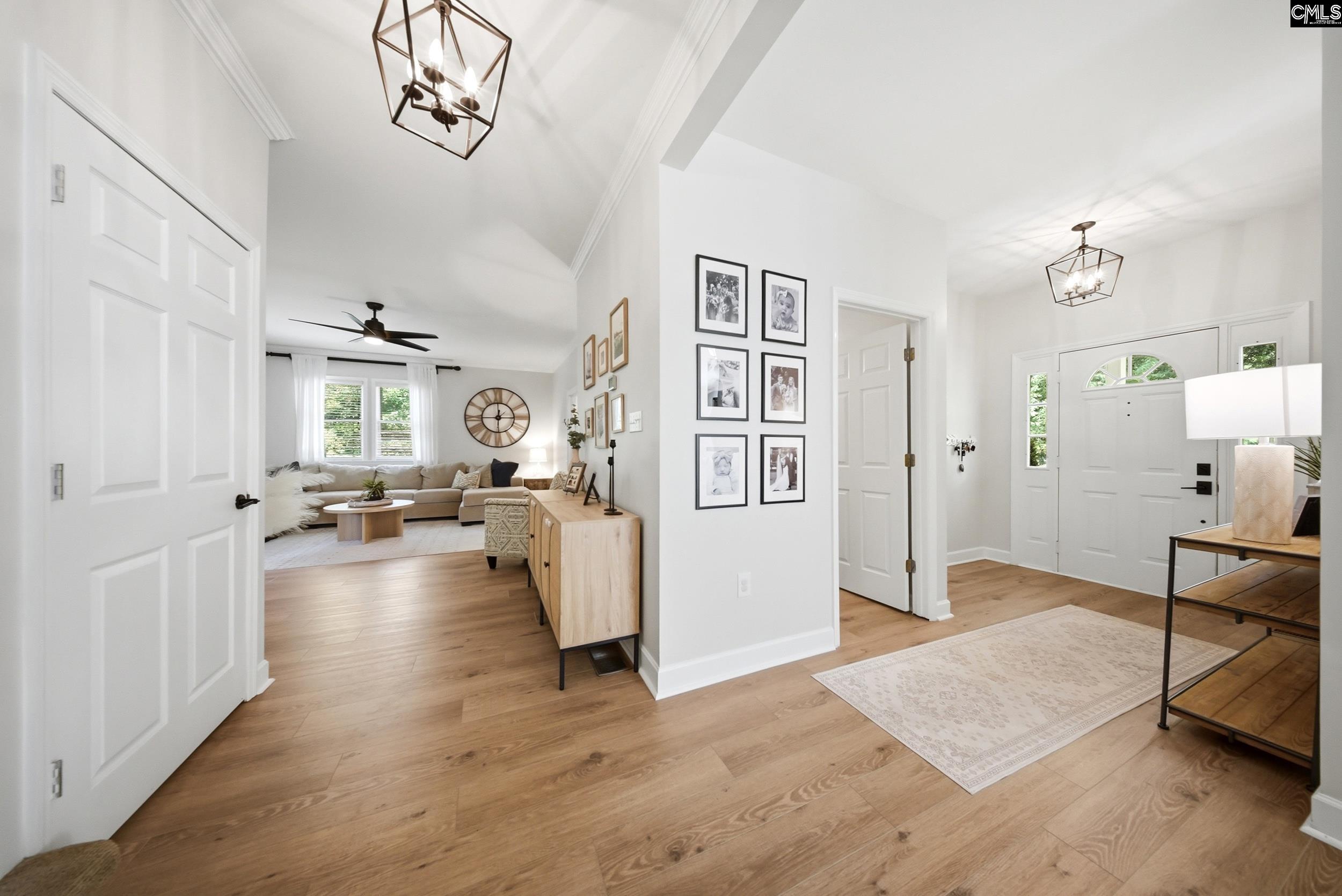 Bright entryway with white double doors, wood floors, and an open living room with a beige sectional.