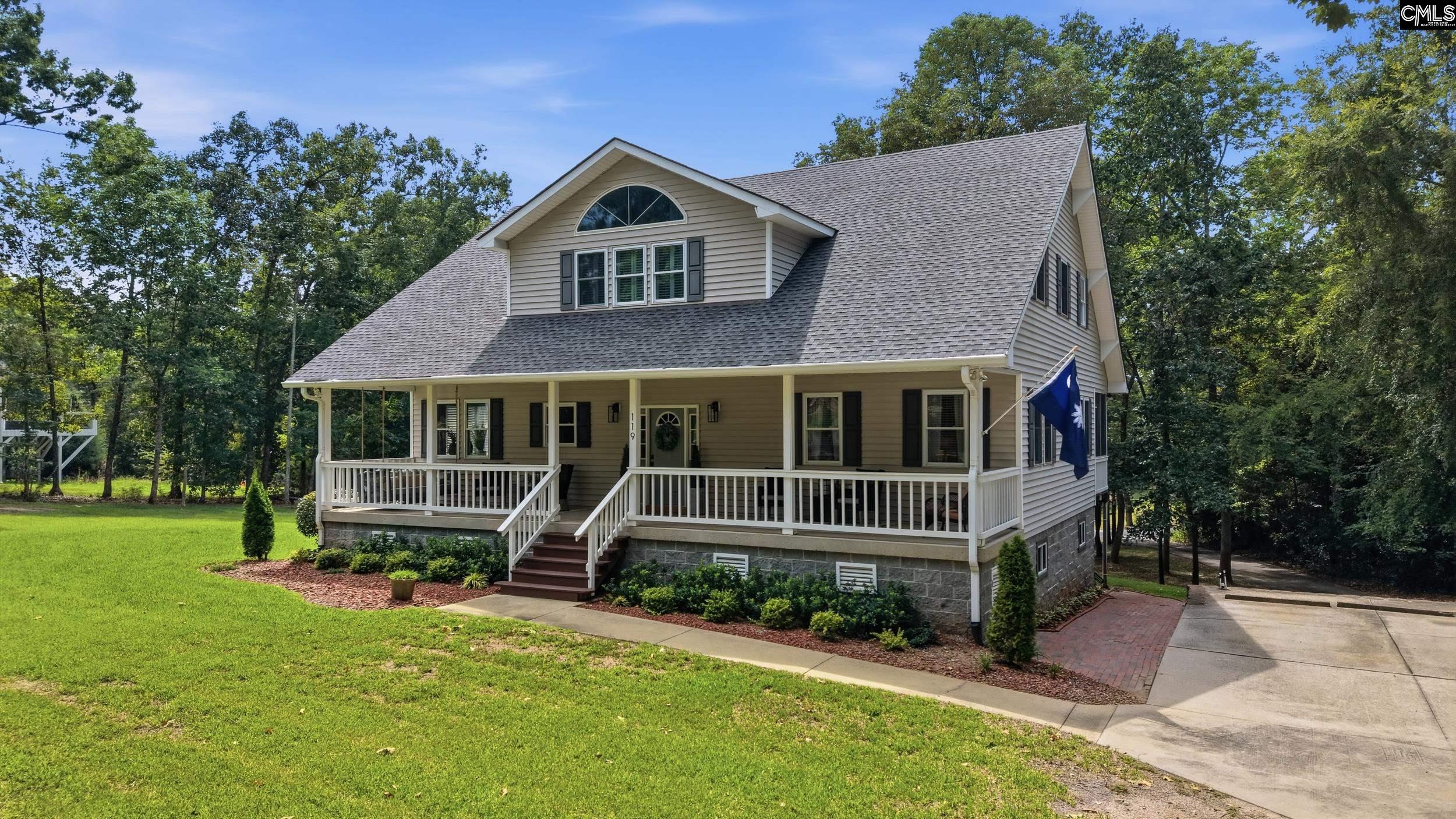 Two-story beige home with a covered porch, white railings, and a South Carolina flag