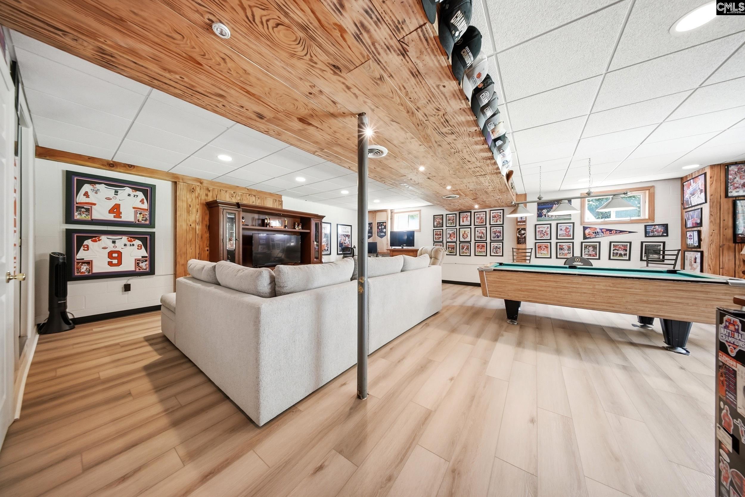 Basement game room with a pool table, sectional sofa, and walls covered in sports memorabilia.