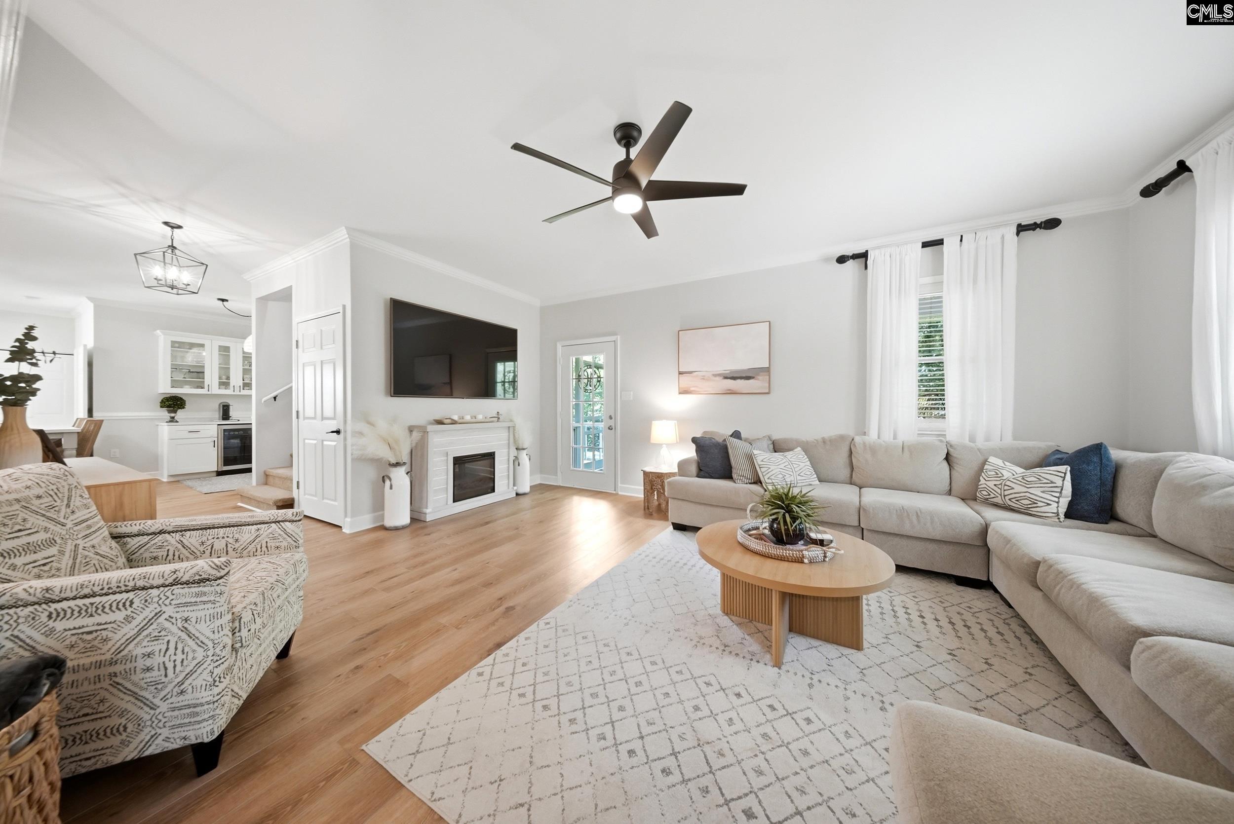 Open-plan living room with a large sectional, fireplace, and kitchen beyond.