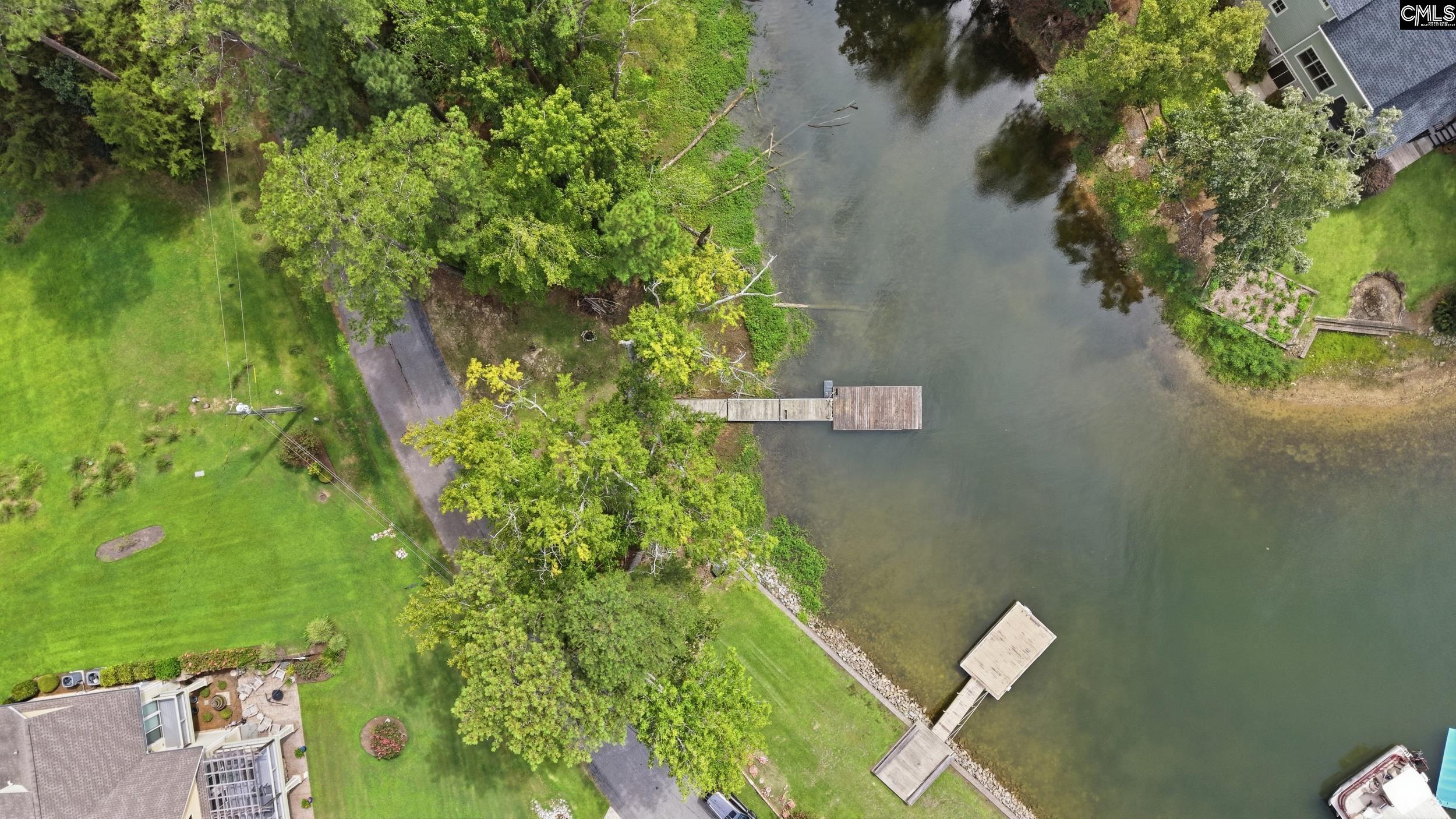 Aerial view of a wooded lakeside property with landscaped lawns and several docks.