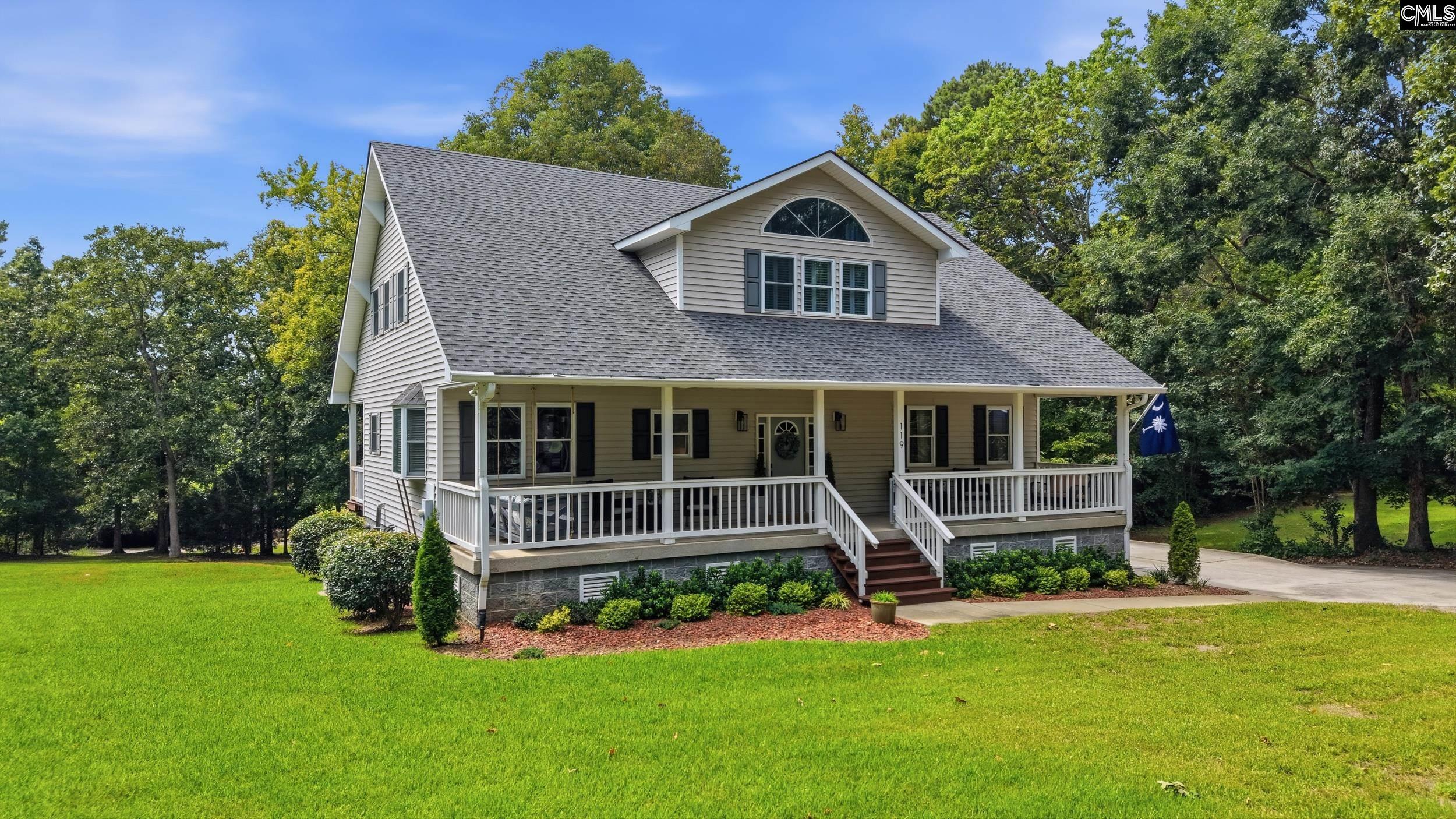 Two-story beige home with a broad covered porch, white railings, and a green lawn.