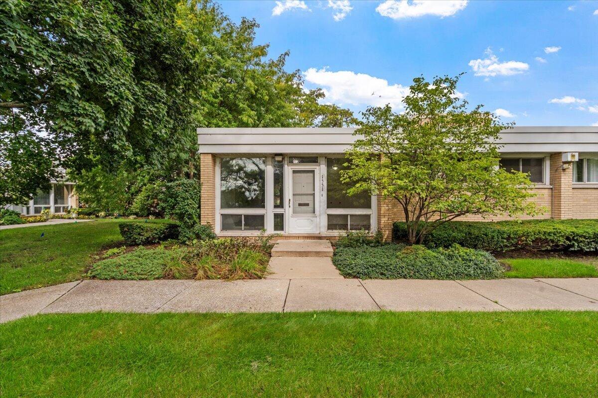 Single-story brick home with a flat roof, broad windows, and a landscaped front yard.