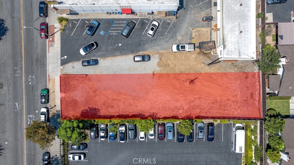 Aerial view of a red-highlighted rectangular property parcel surrounded by parking lots and a street.