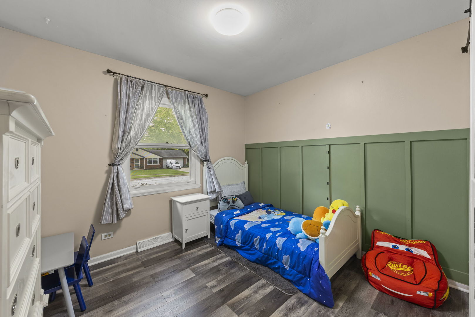 Bedroom with a single bed, green built-in cabinets, and children's toys.