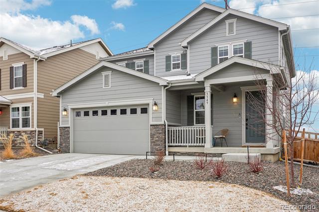 Gray two-story house with a two-car garage, covered porch, and lightly snow-covered lawn.