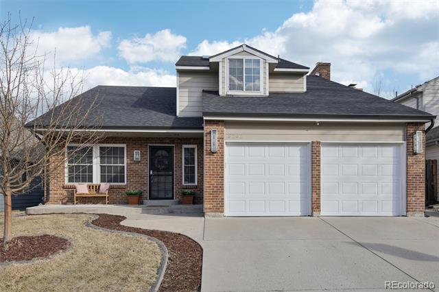 Brick-and-gray-sided home with a dormer, two-car garage, and leafless front-yard tree.
