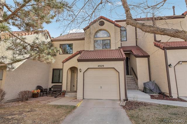 Two-story stucco home with a red tile roof, arched window, and attached garage.
