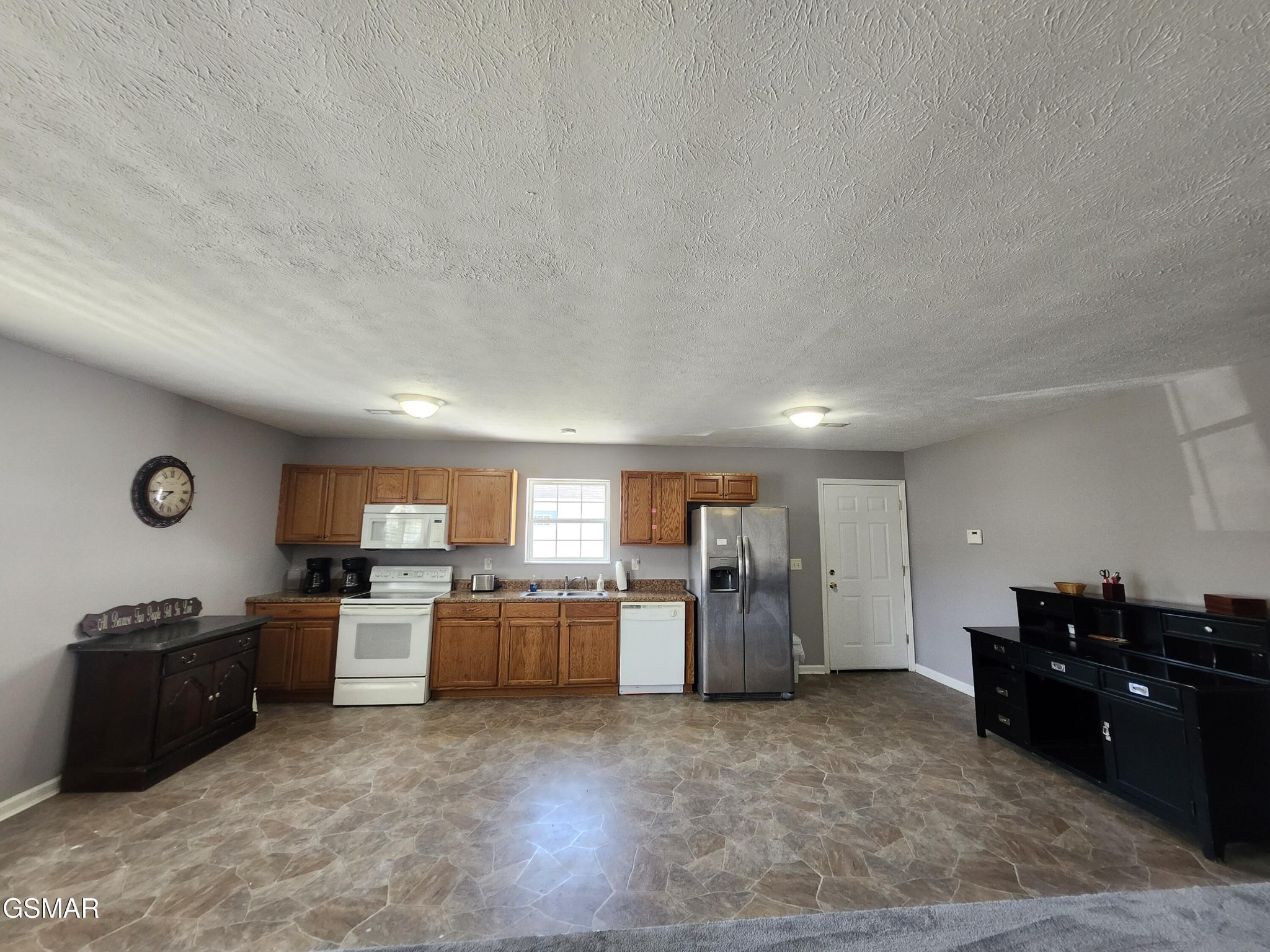 Kitchen with wood cabinets, stainless steel refrigerator, white appliances, and patterned tile floor.
