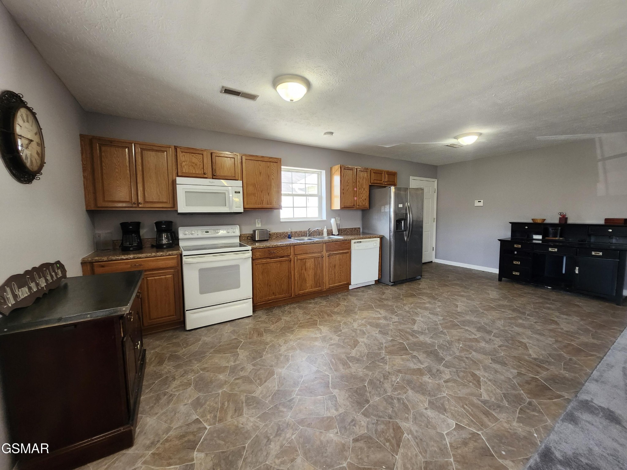 Kitchen with wood cabinets, mixed white and stainless-steel appliances, and patterned stone-look flooring.