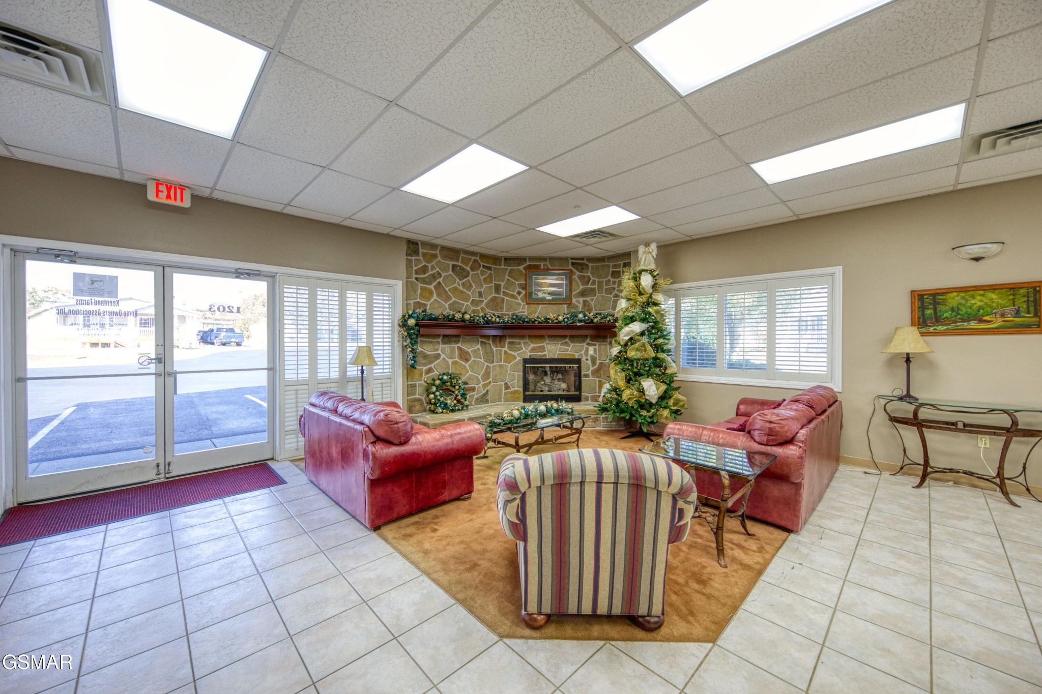 Furnished lounge with stone fireplace, red sofas, and decorated Christmas tree.