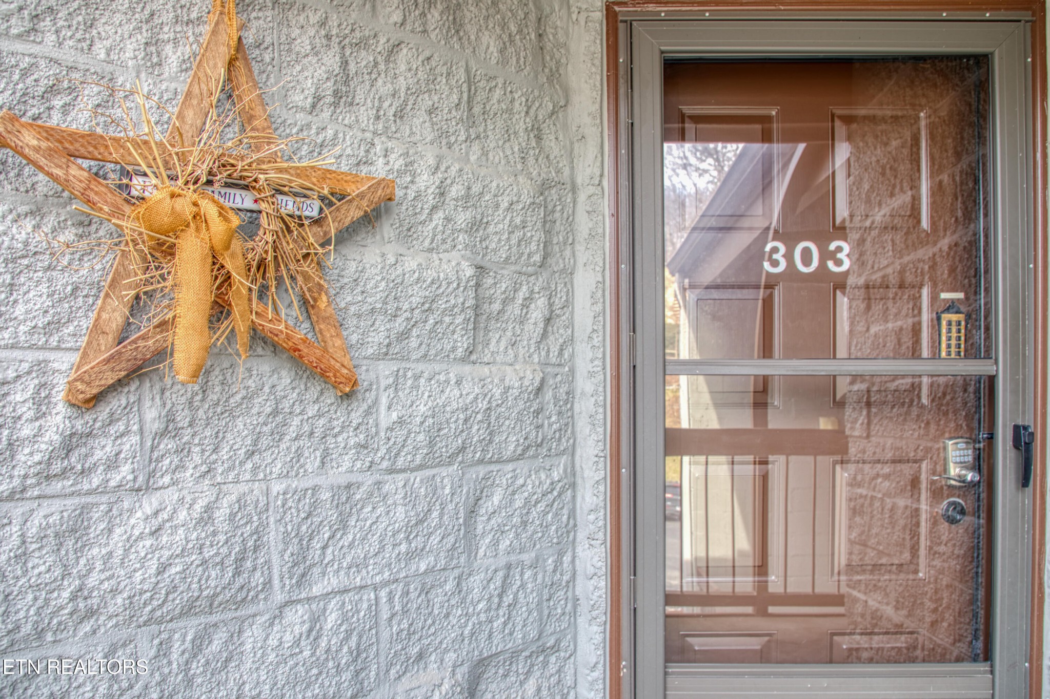 Condo entrance with glass storm door marked 303 and a rustic star wreath.