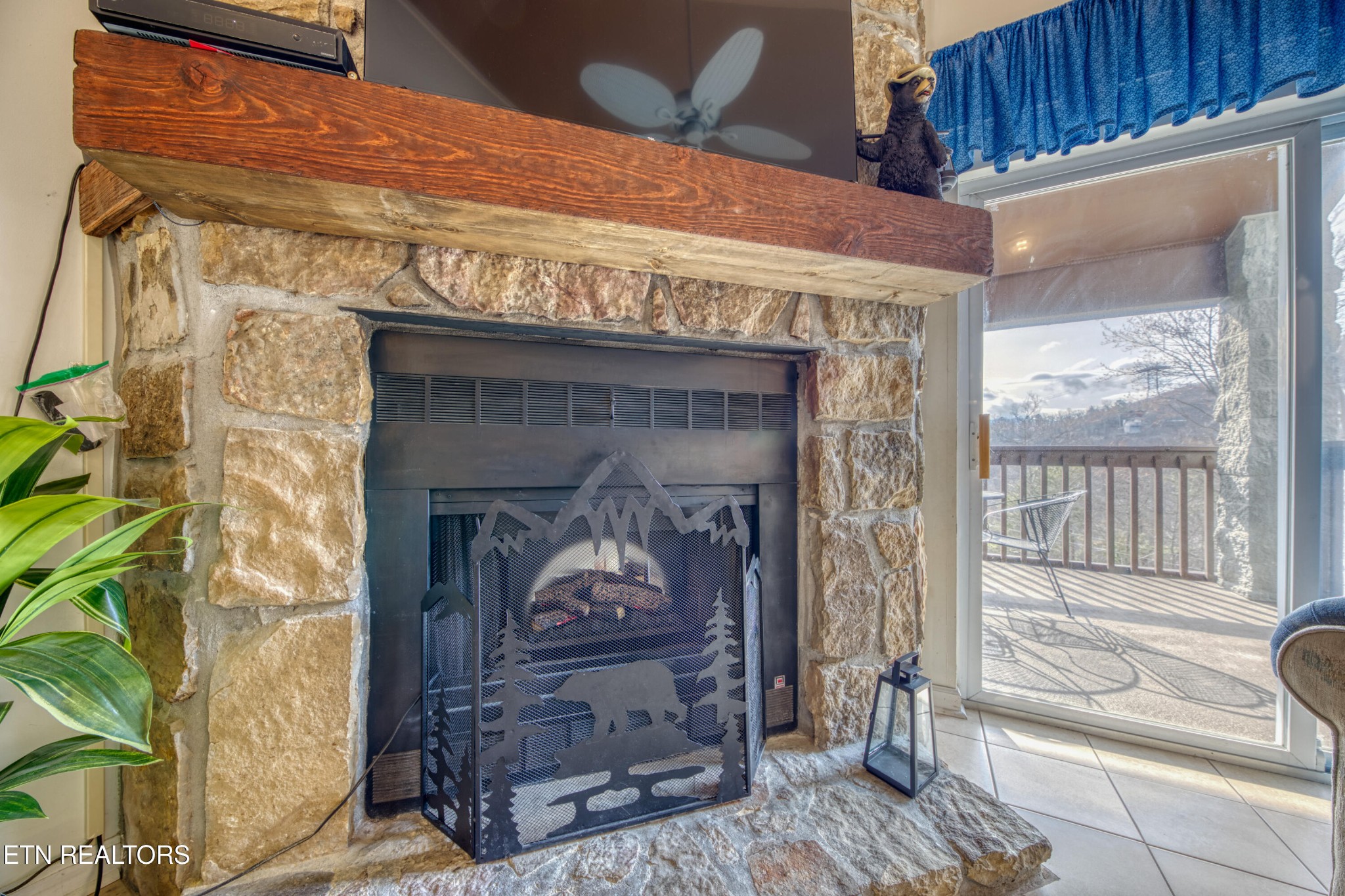 Stone fireplace beside a balcony door with a snowy mountain view.