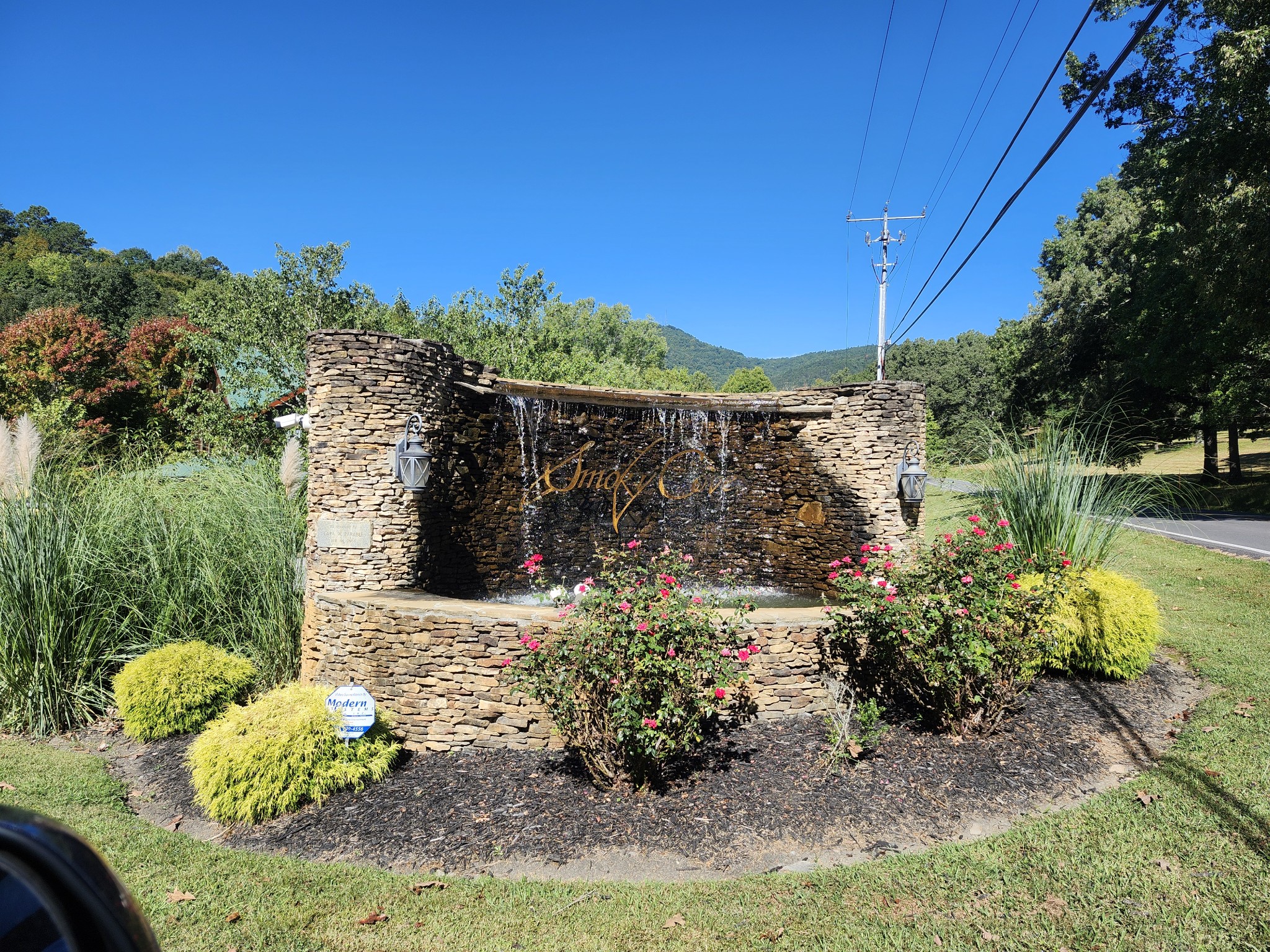 Stone Smoky Cove entrance monument with a cascading fountain and flowering landscaping.
