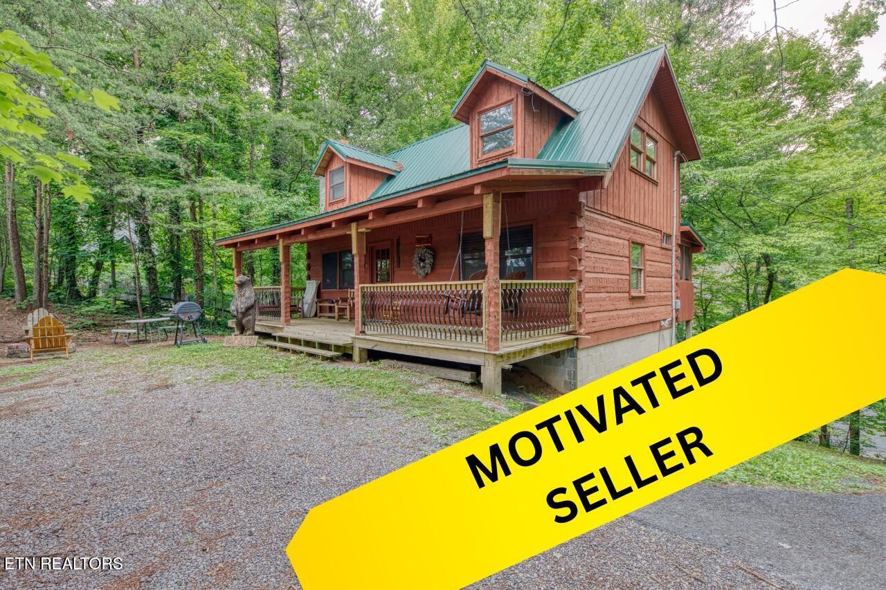 Wooded cabin with a covered porch and green metal roof, marked “Motivated Seller.”