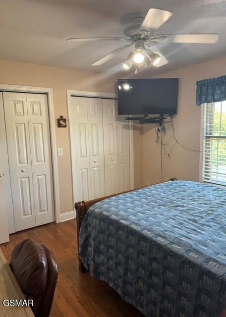 Bedroom with a blue patterned bedspread, wall-mounted television, and white closet doors.