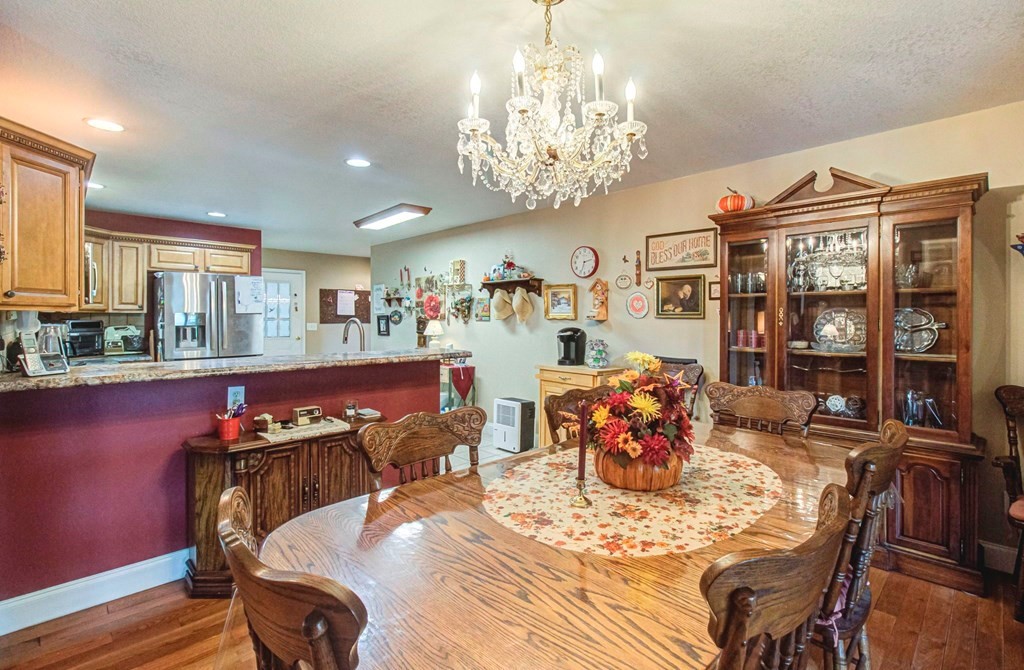 Dining room with a polished wood table, floral centerpiece, carved chairs, and ornate china cabinet.