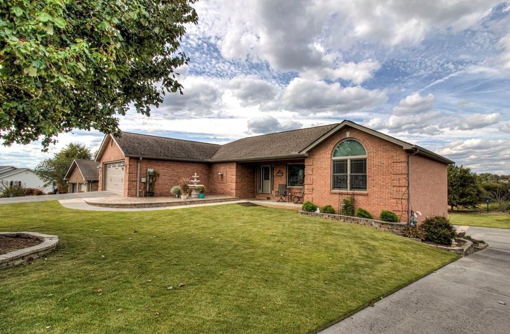 Single-story brick home with an attached garage, arched front window, and broad lawn.