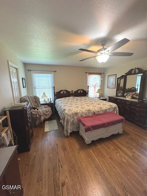 Bedroom with a large bed, dark wood furniture, red bench, and hardwood floors.