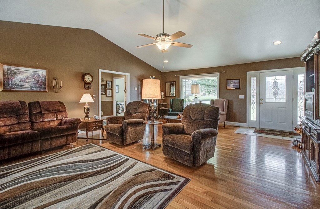 Living room with brown reclining furniture, a patterned rug, and hardwood floors.