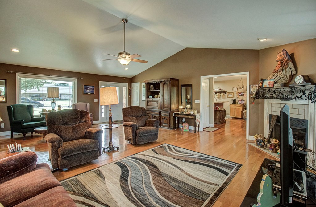 Living room with brown seating, hardwood floors, a patterned rug, and a fireplace topped by a carved wolf.