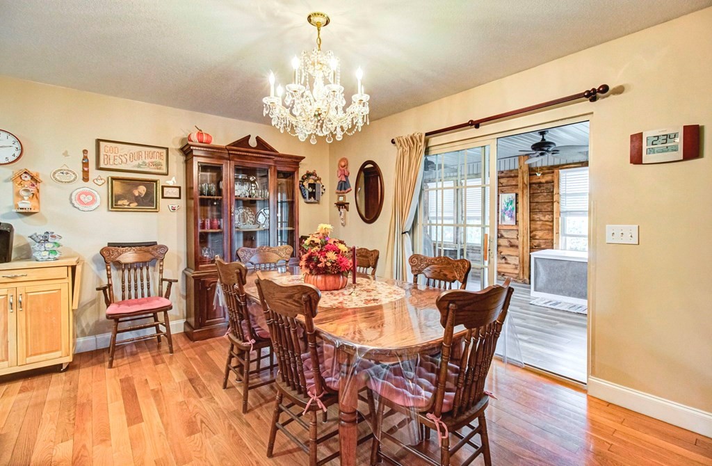 Furnished dining room with a carved wood table, chandelier, china cabinet, and sliding doors to a sunroom.