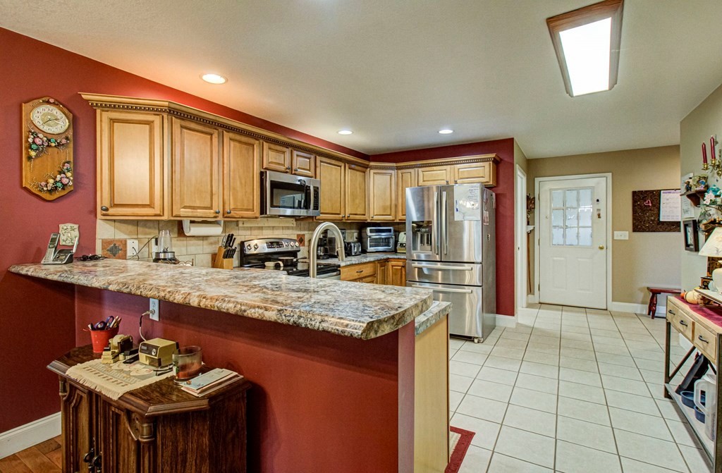 Kitchen with wood cabinets, stainless steel appliances, and a large granite-topped peninsula.