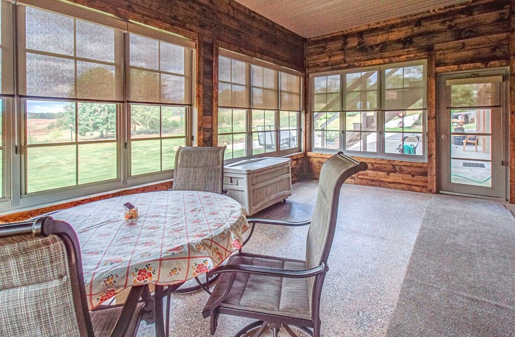 Wood-paneled sunroom with large windows, a round dining table, and an indoor spa tub.