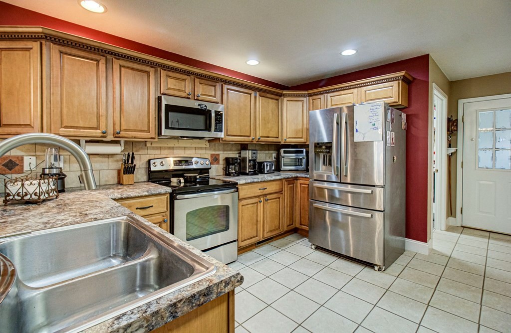 Kitchen with honey-colored cabinets, stainless steel appliances, and a large double-basin sink.