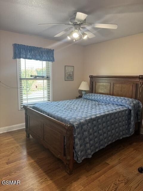 Bedroom with a dark wood bed, blue patterned bedding, and hardwood floors.