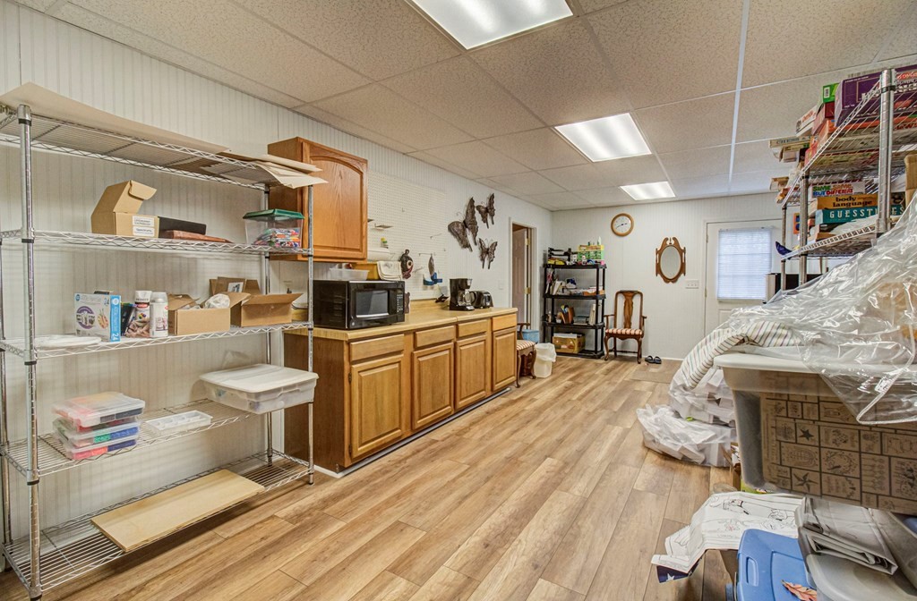 Storage room with wooden cabinets, wire shelving, boxes, and wood-look flooring.