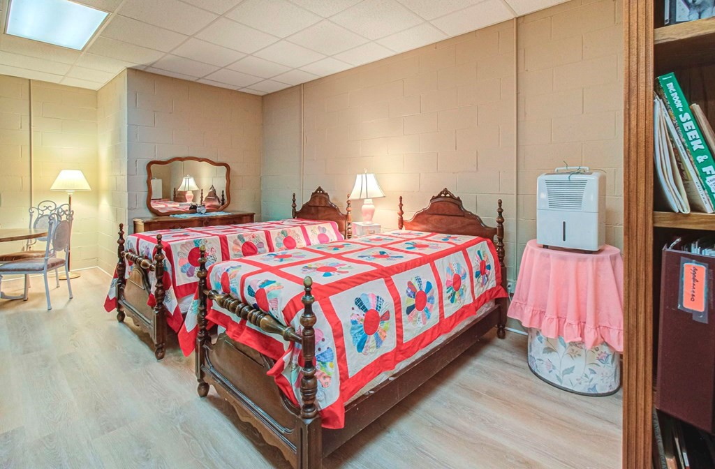Bedroom with two antique wooden beds dressed in colorful patchwork quilts.
