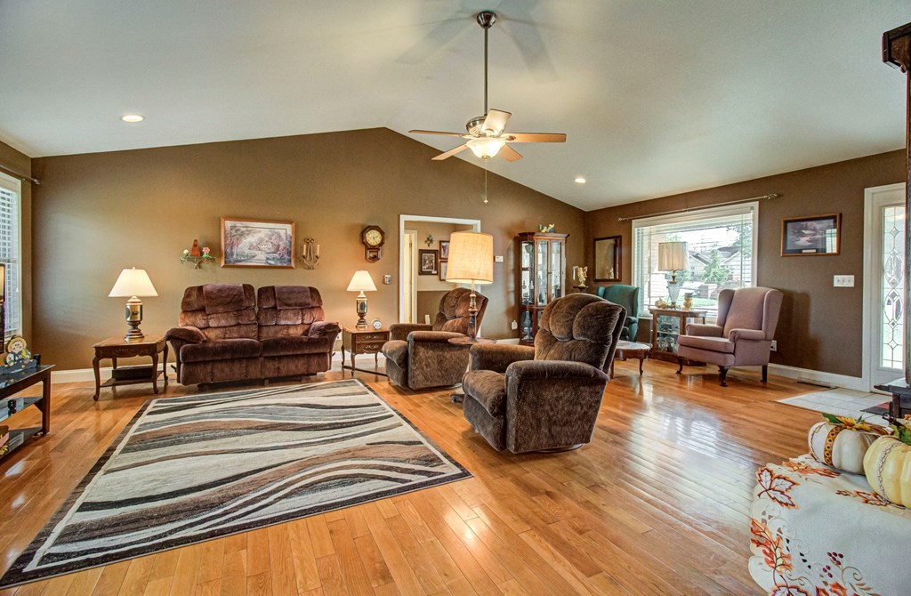 Living room with brown recliners, hardwood floors, a geometric rug, and a bright window seating area.