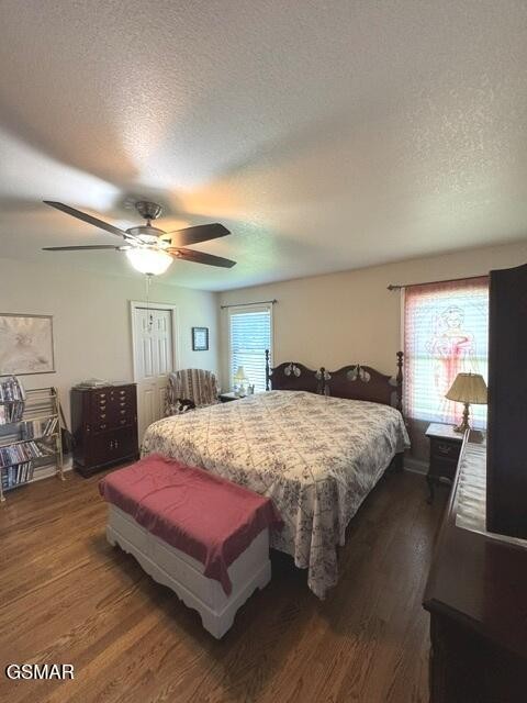 Furnished bedroom with a large bed, hardwood floors, and ceiling fan.