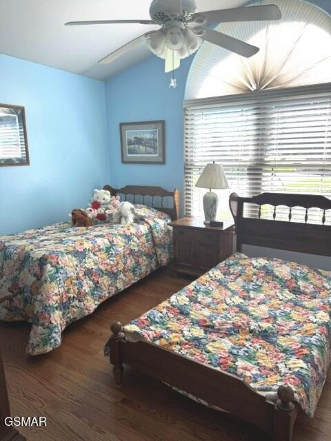 Bedroom with two floral-quilted beds, blue walls, and a large arched window.