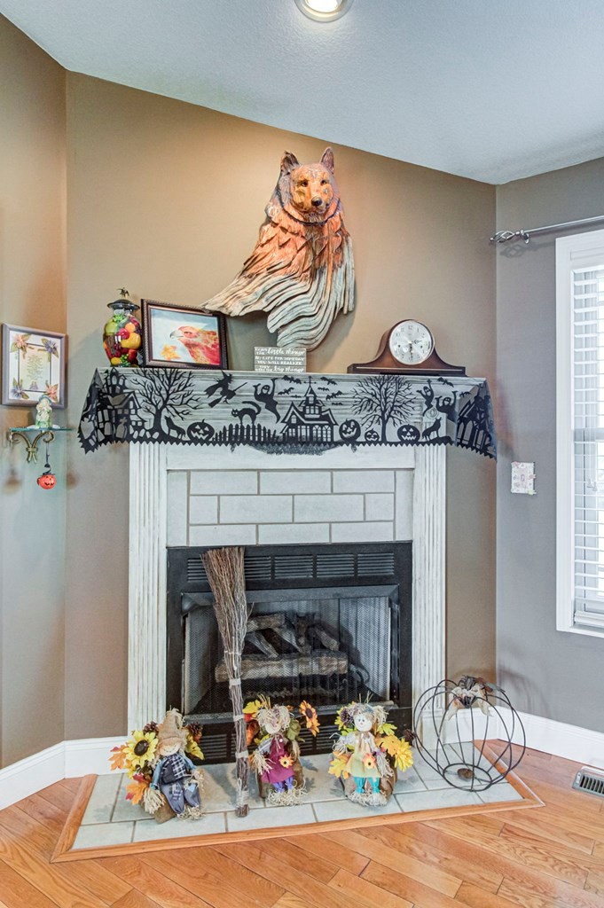 Living room fireplace with Halloween garland, scarecrow figures, and a carved wooden animal above the mantel.