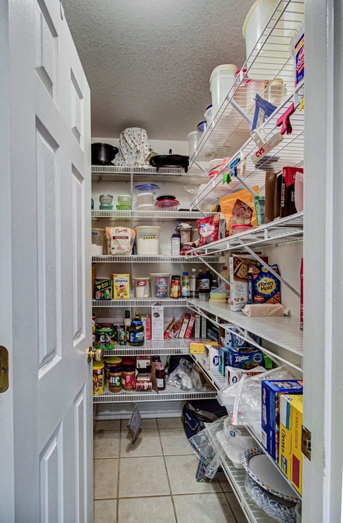 Walk-in pantry with wire shelves stocked with food and household supplies.