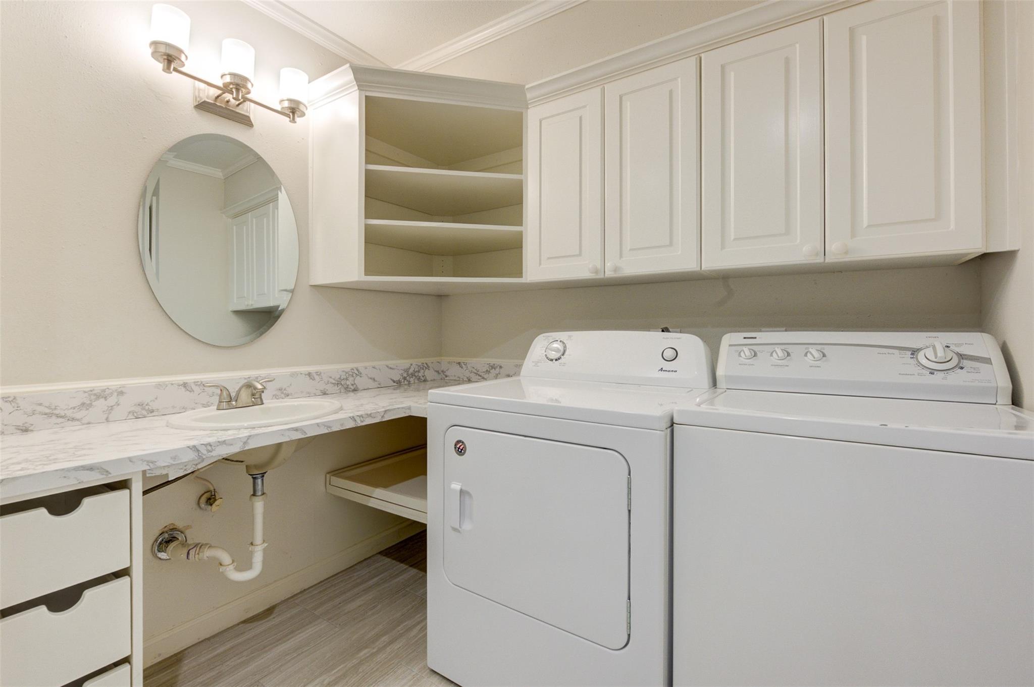 Laundry room with washer and dryer, utility sink, and white cabinets.