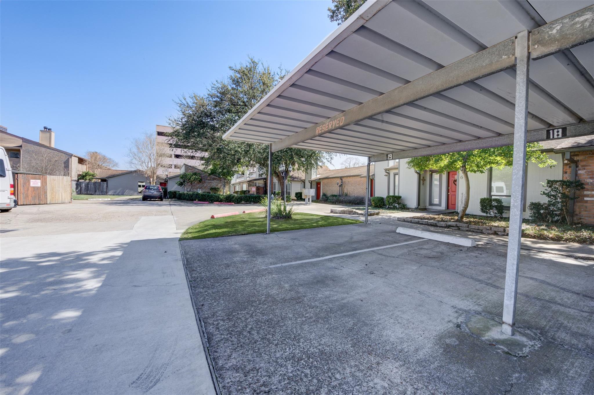 Townhouse complex with covered parking, numbered spaces, and landscaped unit entrances.