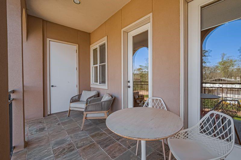 Covered apartment balcony with tiled flooring, a round table, and lounge seating.