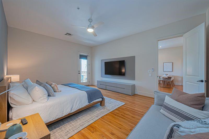Bedroom with a large bed, hardwood floors, and a wall-mounted television.