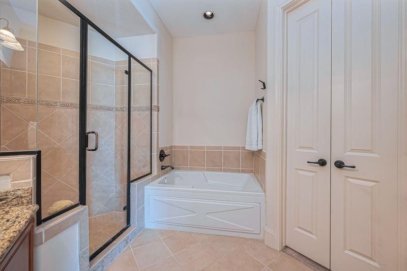 Bathroom with a glass-enclosed shower and built-in bathtub beside white double doors.
