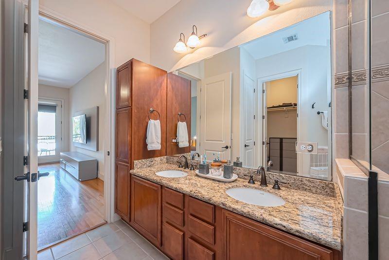 Bathroom with a double-sink granite vanity, dark wood cabinets, and a large mirror.