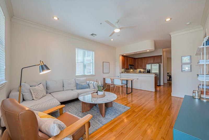 Open-plan living room with a gray sectional, hardwood floors, and kitchen breakfast bar.