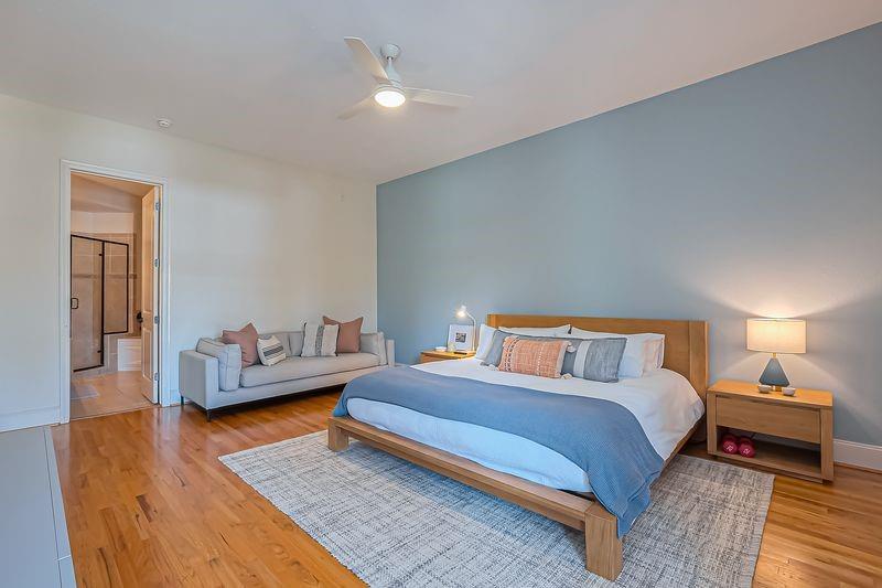 Furnished bedroom with a large bed against a blue accent wall and a sofa seating area.