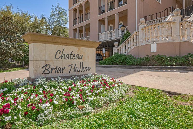 Chateau Briar Hollow residential building entrance with a stone sign and colorful flower bed.